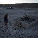 
              Misha McBride looks at a formally sunken boat now on cracked earth hundreds of feet from what is now the shoreline on Lake Mead at the Lake Mead National Recreation Area, Monday, May 9, 2022, near Boulder City, Nev. (AP Photo/John Locher)
            