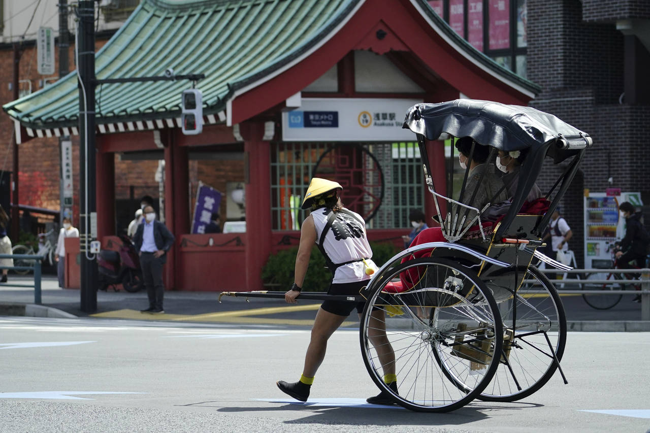 FILE - A rickshaw puller carries tourists near Sensoji Buddhist temple at Tokyo's Asakusa district ...