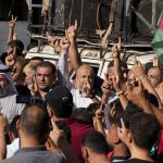 
              Hamas supporters raise their fingers while chanting slogans as others wave Palestinian flags during a protest against the Israeli flags march to mark Jerusalem Day, an Israeli holiday celebrating the capture of the Old City of Jerusalem during the 1967 Mideast war, in the Jebaliya refugee camp, northern Gaza Strip, Sunday, May 29, 2022. (AP Photo/Adel Hana)
            