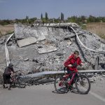 
              FILE - Teenagers on bicycles pass a bridge destroyed by shelling near Orihiv, Ukraine, May 5, 2022. An interminable and unwinnable war in Europe? That's what NATO leaders fear and are bracing for as Russia's war in Ukraine grinds into its third month with little sign of a decisive military victory for either side, and no resolution in sight. (AP Photo/Evgeniy Maloletka, File)
            