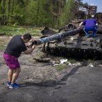 
              A man takes photos of a destroyed Russian tank, on the outskirts of Kyiv, Ukraine, Sunday, May 8, 2022. (AP Photo/Emilio Morenatti)
            