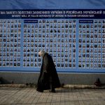 
              A woman walks past the Memorial Wall of Fallen Defenders of Ukraine in Russian-Ukrainian War in Kyiv, Ukraine, Monday, May 23, 2022. (AP Photo/Natacha Pisarenko)
            