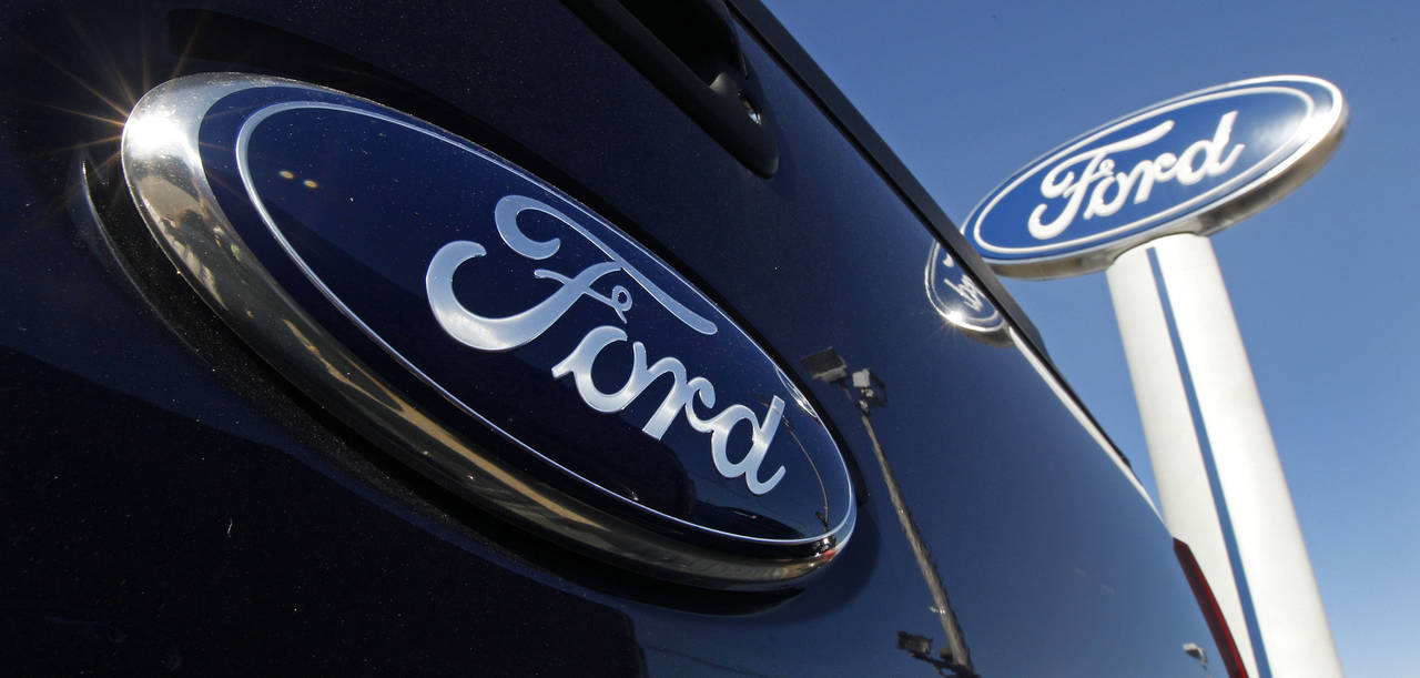 FILE - A Ford logo, on the tailgate of a 2012 F350 Super Duty pick-up truck, and Ford dealership si...