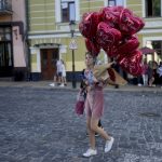 
              A woman crosses a street with balloons in Kyiv, Ukraine, Wednesday, June 1, 2022. (AP Photo/Natacha Pisarenko)
            