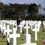 A woman holds a bouquet of roses during the 78th anniversary of D-Day ceremony, in the Normandy American Cemetery and Memorial of Colleville-sur-Mer, overlooking Omaha Beach, Monday, June, 6, 2022. The ceremonies pay tribute to the nearly 160,000 troops from Britain, the U.S., Canada and elsewhere who landed on French beaches on June 6, 1944, to restore freedom to Europe after Nazi occupation. (AP Photo/ Jeremias Gonzalez)