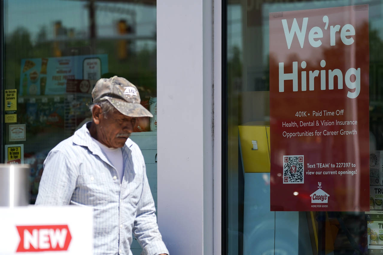 A hiring sign is displayed at a gas station as a customer walks past in Buffalo Grove, Ill., Thursd...