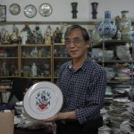 
              Joseph Tso, owner of Yuet Tung China Works, Hong Kong's last hand-painted porcelain factory, holds a plate with UK royal print in Hong Kong, Wednesday, June 8, 2022. Tso, the third-generation owner of the factory, and his small team are among the few people in Hong Kong who have mastered the traditional technique of painting “guangcai,” or Canton porcelain.  (AP Photo/Kin Cheung)
            