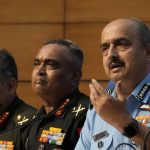 
              Indian Air Force Chief Air Chief Marshal V R Chaudhari speaks with Indian Army chief General Manoj Pande seated beside him during the launch of Agnipath Scheme, in New Delhi, Tuesday, June 14, 2022. The Agnipath is a merit based recruitment scheme for enrolling soldiers, airmen and sailors. The Scheme provides an opportunity for the youth to serve in the regular cadre of the armed forces for a duration of four years. (AP Photo/Manish Swarup)
            