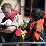 
              A soldier carries a child from a group of people thought to be migrants are brought in to Dover, England, by Border Force, following a small boat incident in the Channel, Tuesday June 14, 2022. (Andrew Matthews/PA via AP)
            