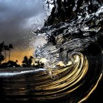 In this undated photo entitled "Obsidian," a breaking wave is lit by the camera's flash as the sun sets on the North Shore of Oahu near Haleiwa, Hawaii. The image appears in photographer Clark Little's new book, "The Art of Waves." (Clark Little via AP)