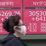 A woman wearing a protective mask rides a bicycle in front of an electronic stock board showing Japan's Nikkei 225 and New York Dow Jones indexes at a securities firm Wednesday, June 22, 2022, in Tokyo. Asian shares were mostly lower Wednesday as markets shrugged off a Wall Street rally and awaited congressional testimony by Federal Reserve Chair Jerome Powell. (AP Photo/Eugene Hoshiko)