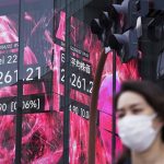 A woman wearing a protective mask rides a bicycle in front of an electronic stock board showing Japan's Nikkei 225 index at a securities firm Wednesday, June 22, 2022, in Tokyo. Asian shares were mostly lower Wednesday as markets shrugged off a Wall Street rally and awaited congressional testimony by Federal Reserve Chair Jerome Powell. (AP Photo/Eugene Hoshiko)