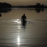 
              A man walks in the water as the sun rises above the Miribel lake, outside Lyon, central France, Saturday, June 18, 2022. A blanket of hot air stretching from the Mediterranean to the North Sea is giving much of western Europe its first heat wave of the summer, with temperatures forecast to top 30 degrees Celsius (86 degrees Fahrenheit) from Malaga to London on Friday. (AP Photo/Laurent Cipriani)
            