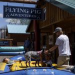 
              Patrick Sipp, co-owner of Flying Pig Adventures, pets his dog, Bonnie, as employees Jackson Muller, right, and Christie Davis sit in a raft while Yellowstone National Park is closed due to historic flooding in Gardiner, Mont., Wednesday, June 15, 2022. "We're definitely a resilient company, we've got a very tough crew," Sipp said. "But it's devastating. You just hate seeing stuff like that in the community. We're just hoping that we can get back out there relatively soon." (AP Photo/David Goldman)
            