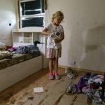 
              Harlee Holmes, 8, cleans out her room as her family is forced to leave their home left damaged by severe flooding in Fromberg, Mont., Friday, June 17, 2022. (AP Photo/David Goldman)
            