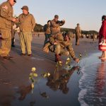 
              World War II reenactors put roses and flowers at dawn on Omaha Beach, in Saint-Laurent-sur-Mer, Normandy, France Monday, June 6, 2022, the day of 78th anniversary of the assault that helped bring an end to World War II. (AP Photo/Jeremias Gonzalez)
            