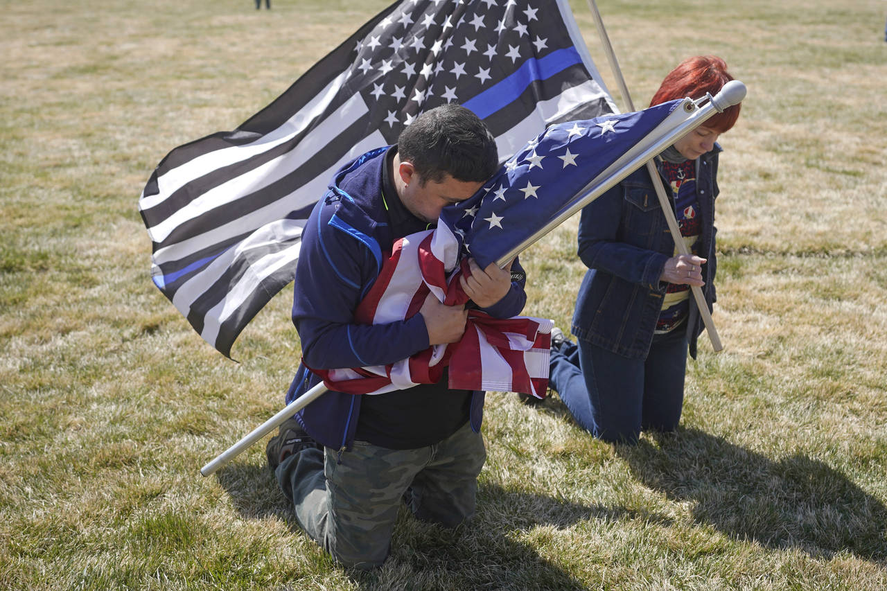 FILE - Marius Annandale kneels while praying during a Second Amendment gun rights rally at the Utah...