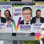 
              FILE - A woman walks past election posters reading "Melenchon Prime Minister", for the alliance of leftist parties cobbled together by hard-left leader Jean-Luc Melenchon, in Saint Jean de Luz, southwestern France, Friday, June 10, 2022. French voters were choosing lawmakers in a parliamentary election Sunday, June 12, 2022 as President Emmanuel Macron seeks to secure his majority while under growing threat from a leftist coalition. (AP Photo/Bob Edme, File)
            