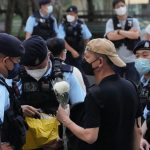 
              Police officers stop and search a man holding a flower at the Hong Kong's Victoria Park, Saturday, June 4, 2022. Dozens of police officers patrolled Hong Kong's Victoria Park on Saturday after authorities for a second consecutive third banned public commemoration of the anniversary of the Tiananmen Square crackdown in 1989, amid a crackdown on dissent in the city. (AP Photo/Kin Cheung)
            