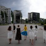 
              Girls dance near a building destroyed in Russian attacks, in Borodyanka, on the outskirts of Kyiv, Ukraine, Tuesday, June 21, 2022. (AP Photo/Natacha Pisarenko)
            