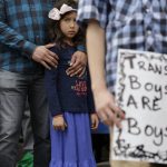 FILE - Libby Gonzales stands with her father, Frank Gonzales, as she joins other members of the transgender community during a rally on the steps of the Texas Capitol, Monday, March 6, 2017, in Austin, Texas. The group is opposing a "bathroom bill" that would require people to use public bathrooms and restrooms that correspond with the sex on their birth certificate. (AP Photo/Eric Gay, File)