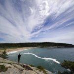 
              CORRECTS YEAR TO 2022 INSTEAD OF 2002 - A man takes in the view of Sand Beach from a rocky overlook in Acadia National Park, Saturday, June 11, 2022, near Bar Harbor, Maine. The park will not have lifeguards on duty this summer due to worker and housing shortages. (AP Photo/Robert F. Bukaty)
            
