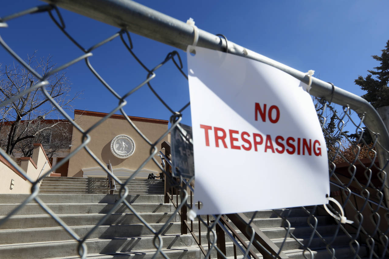 FILE - A sign hangs on a fence around the State Capitol in Santa Fe, on Wednesday, Feb. 24, 2021. R...