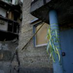 
              Ribbons in the colors of the Ukraine flag are tied to a building destroyed by attacks in Gorenka, on the outskirts of Kyiv, Ukraine, Wednesday, June 8, 2022. (AP Photo/Natacha Pisarenko)
            