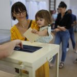 
              A girl casts the ballot for her mother at a voting station in Strasbourg, eastern France, Sunday June 12, 2022, Sunday, June 12, 2022. French voters are choosing lawmakers in a parliamentary election as President Emmanuel Macron seeks to secure his majority while under growing threat from a leftist coalition. (AP Photo/Jean-Francois Badias)
            