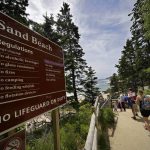 
              CORRECTS YEAR TO 2022 INSTEAD OF 2002 - Beachgoers walk by a sign that warns of the absence of lifeguards at Sand Beach in Acadia National Park, Saturday, June 11, 2022, near Bar Harbor, Maine. (AP Photo/Robert F. Bukaty)
            