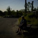 
              Olga Vasilyevna sits outside her home in Gorenka, on the outskirts of Kyiv,  Ukraine, Wednesday, June 8, 2022. Vasilyevna says that after attacks she still has no water nor electricity. (AP Photo/Natacha Pisarenko)
            