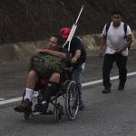 
              Venezuelan migrant Jesus Gonzalez, who broke his leg while crossing the Darien jungle, is pushed in a wheelchair along the Huehuetan highway in the state of Chiapas, Mexico, Tuesday, June 7, 2022. Venezuelans make up a large proportion of this caravan, the biggest of the year, in contrast to others in previous years. (AP Photo/Marco Ugarte)
            