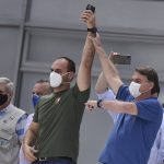 
              FILE - Brazil's President Jair Bolsonaro, right, raises the arm of his son Eduardo Bolsonaro during a protest, in Brasilia, Brazil, May 17, 2020. Bolsonaro, who has distributed at least 76 of the three top medals to ministers since 2019, more than any of his three elected predecessors throughout their two terms, also gave three medals of various sorts to his wife Michelle and senator son Flavio. His son Eduardo, a lawmaker, has been honored with at least six. (AP Photo/Andre Borges, File)
            