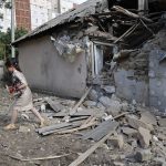 
              A girl carries a dog as she walks past a house damaged from shelling in the Leninsky district of Donetsk, on the territory which is under the Government of the Donetsk People's Republic control, eastern Ukraine, Monday, June 6, 2022. (AP Photo/Alexei Alexandrov)
            