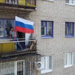 
              In this handout photo taken from video released by Russian Defense Ministry Press Service on Monday, July 4, 2022, A man sets a Russian national flag on a balcony of a residential building in Lysychansk, which is now territory under the Government of the Luhansk People's Republic control, eastern Ukraine. (Russian Defense Ministry Press Service via AP)
            
