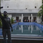 
              A man takes selfie at the swimmimg pool of the official residence of president Gotabaya Rajapaksa three days after it was stormed by anti government protesters in Colombo in Colombo, Sri Lanka, Tuesday, July 12, 2022. A political vacuum continues in Sri Lanka with opposition leaders yet to agree on who should replace its roundly rejected leaders, whose residences are occupied by protesters angry over the country's deep economic woes. (AP Photo/Rafiq Maqbool)
            