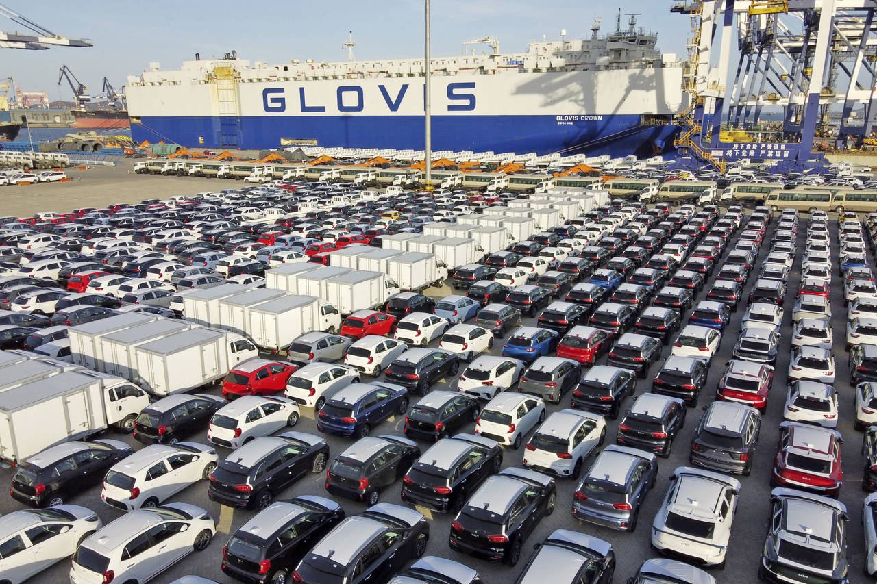 FILE - Cars and trucks for export are parked at a port in Yantai in eastern China's Shandong Provin...