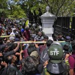 
              Protesters use an iron barricade to break the gate as they storm the compound of Sri Lankan Prime Minister Ranil Wickremesinghe's office, demanding he resign after president Gotabaya Rajapaksa fled the country amid economic crisis in Colombo, Sri Lanka, Wednesday, July 13, 2022. Sri Lanka’s president fled the country without stepping down Wednesday, plunging a country already reeling from economic chaos into more political turmoil. Protesters demanding a change in leadership then trained their ire on the prime minister and stormed his office. (AP Photo/Eranga Jayawardena)
            