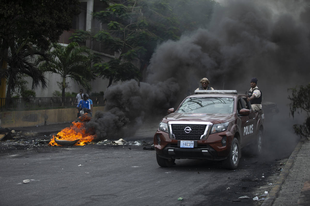 Police drive their car over a barricade set up by taxi drivers to protest fuel shortages in Port-au...
