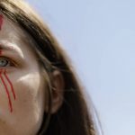 
              Olha Maliuchenko, the fiancé of a Ukrainian soldier from the Azov Regiment who was captured by Russia in May after the fall of Mariupol, wears paint depicting blood on her face during a rally in Kyiv, Ukraine, Saturday, July 30, 2022. The rally comes a day after Russian and Ukrainian officials blamed each other for the deaths of dozens of Ukrainian prisoners of war in an attack Friday on a prison in a separatist-controlled area of eastern Ukraine. Maliuchenko has no information on the well-being of her fiancé. (AP Photo/David Goldman)
            