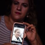
              Ana Morazan, of Honduras, shows a photo of her at work as a home health aide on her phone at a migrant shelter Thursday, June 30, 2022, in the border city of Tijuana, Mexico. Back-to-back hurricanes destroyed her home in Honduras in 2020, forcing her to join the millions of people uprooted by rising seas, drought, searing temperatures and other climate catastrophes. (AP Photo/Gregory Bull)
            