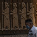 
              FILE - A Parsi man walks next to a bas-relief depicting early Zoroastrians at a Parsi colony on Nowruz, the Parsi New Year, in Mumbai, India, Monday, March 21, 2022. Parsis, also known as Zoroastrians, worship fire and are followers of the Bronze Age Persian prophet Zarathustra. (AP Photo/Rafiq Maqbool, File)
            