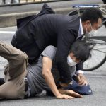 
              Tetsuya Yamagami, bottom, is detained near the site of gunshots in Nara Prefecture, western Japan, Friday, July 8, 2022. Former Japanese Prime Minister Shinzo Abe, an arch-conservative and one of his nation's most divisive figures, was shot and critically wounded by Yamagami, during a campaign speech Friday in western Japan. He was airlifted to a hospital but officials said he was not breathing and his heart had stopped.(Katsuhiko Hirano/The Yomiuri Shimbun via AP)
            