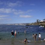 Visitors line an iconic beach at the La Jolla Friday, June 17, 2022, in San Diego. The summer of 2022 can feel as if the coronavirus pandemic is really over, as tourists flock to the area's famous beaches. (AP Photo/Gregory Bull)