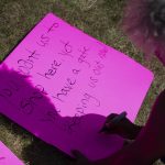 
              Cariol Horne, 54, makes a sign to hold as she stands outside the fenced-off parking lot outside Tops Friendly Market during a remembrance ceremony on Thursday, July 14, 2022, in Buffalo, N.Y. (AP Photo/Joshua Bessex)
            