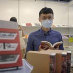 
              Gabriel Tsang, in his 30s, a novelist, holds his book at a booth during the book fair in Hong Kong, Wednesday, July 20, 2022. (AP Photo/Kin Cheung)
            