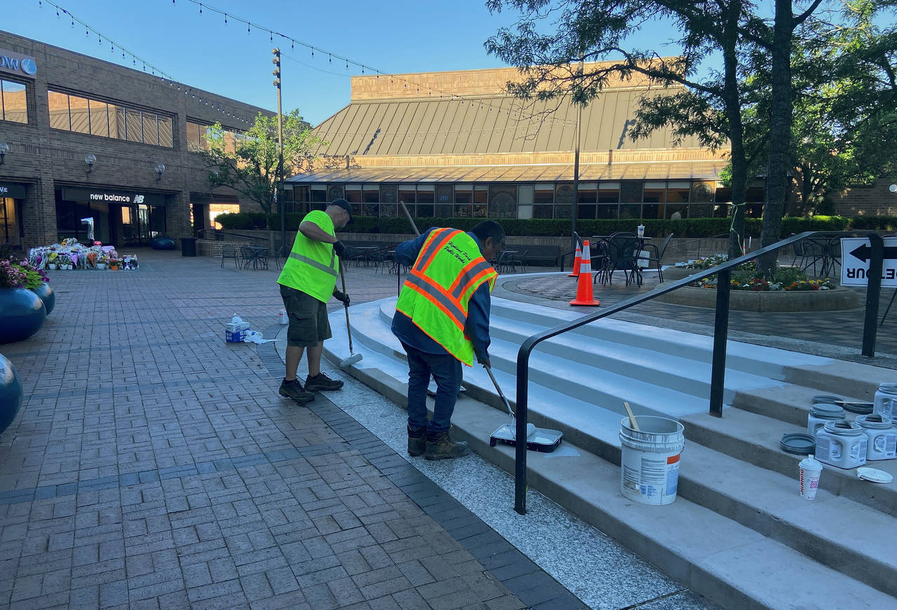 This image provided by Nancy Schneider shows workers painting steps in a business district that reo...