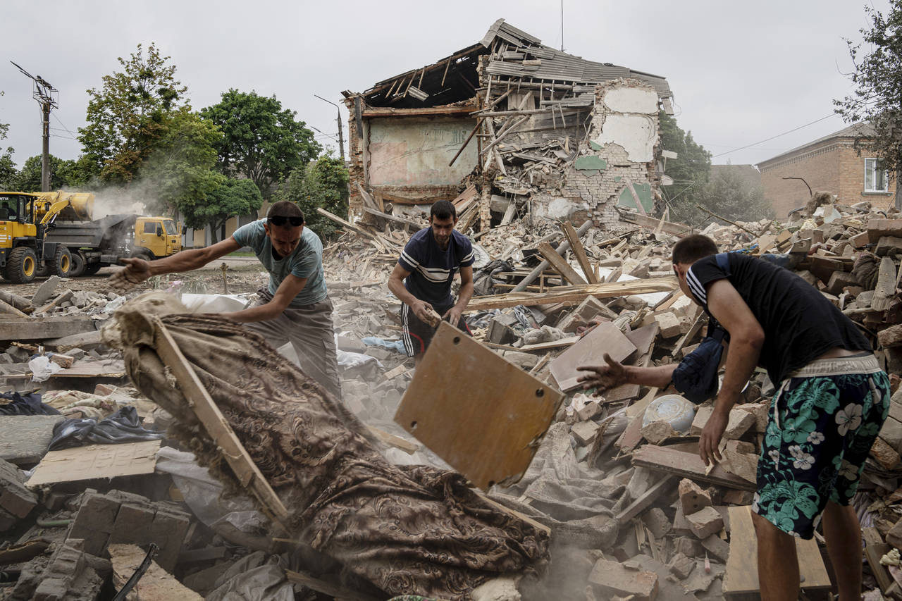 Local residents search for documents of their injured friend in the debris of a destroyed apartment...