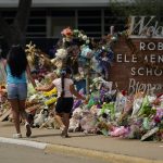 
              Visitors walk past a makeshift memorial honoring those recently killed at Robb Elementary School, Tuesday, July 12, 2022, in Uvalde, Texas. A Texas lawmaker says surveillance video from the school hallway where police waited as a gunman opened fire in a fourth-grade classroom will be shown this weekend to residents of Uvalde. (AP Photo/Eric Gay)
            