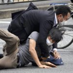 
              Tetsuya Yamagami, bottom, is detained near the site of gunshots in Nara Prefecture, western Japan, Friday, July 8, 2022. Former Japanese Prime Minister Shinzo Abe, a divisive arch-conservative and one of his nation's most powerful and influential figures, has died after being shot during a campaign speech Friday in western Japan, hospital officials said. Nara prefectural police confirmed the arrest of Yamagami, 41, on suspicion of attempted murder of Japan's former Prime Minister Shinzo Abe.(Katsuhiko Hirano/The Yomiuri Shimbun via AP)
            